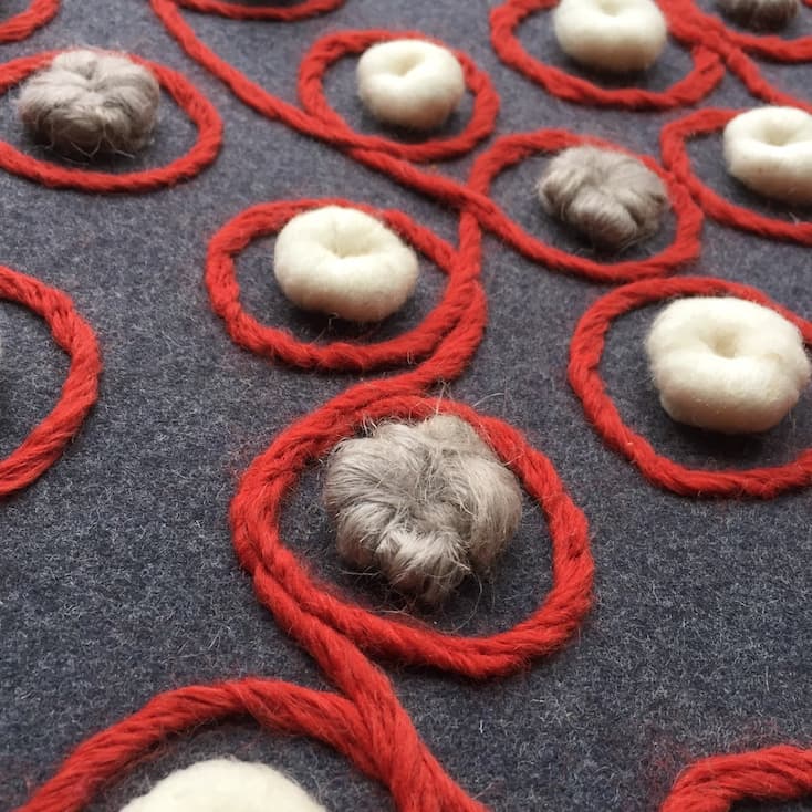 White and grey pebbles with red wool