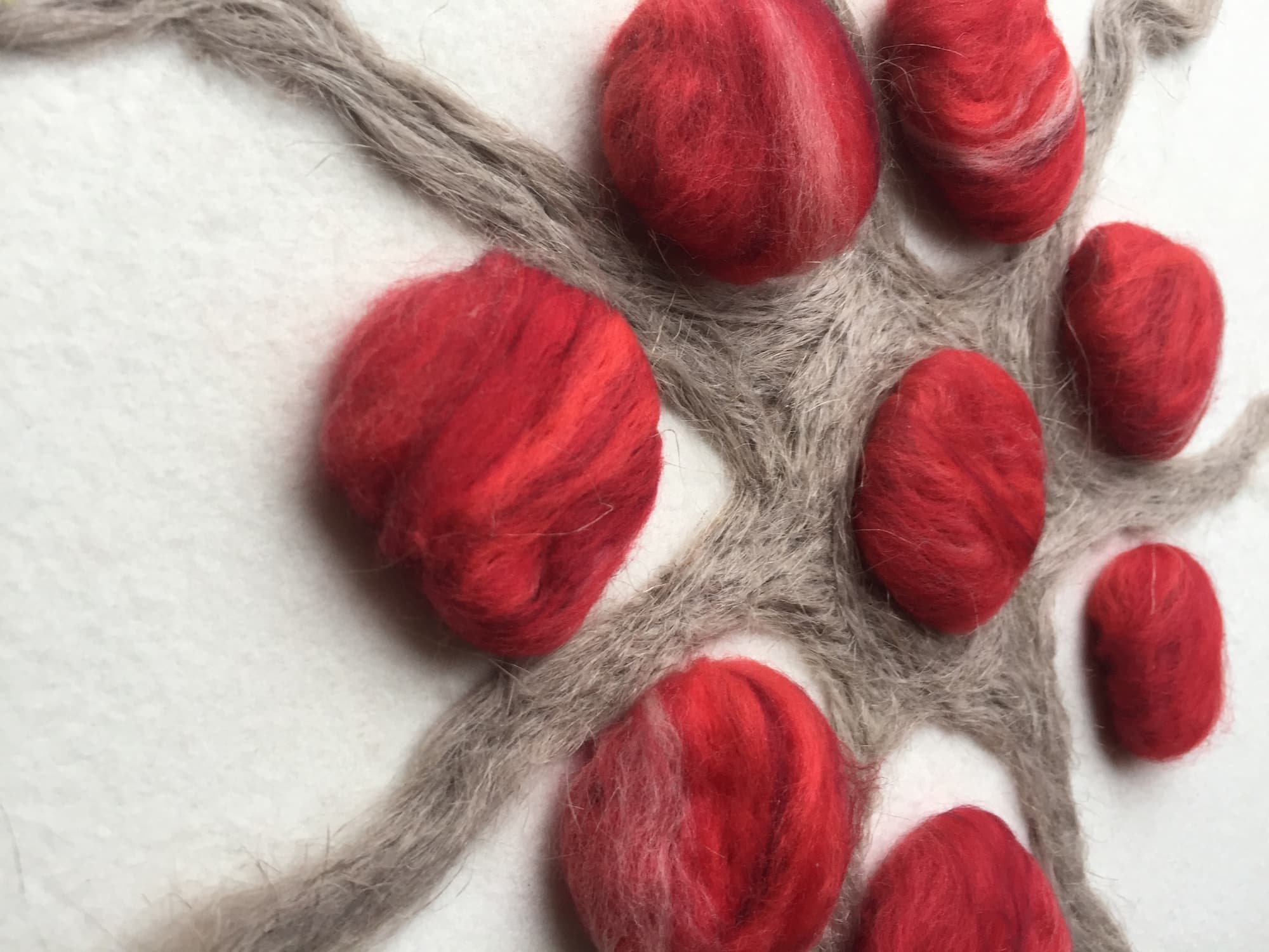 Close-up of red wool clusters arranged like berries on linen